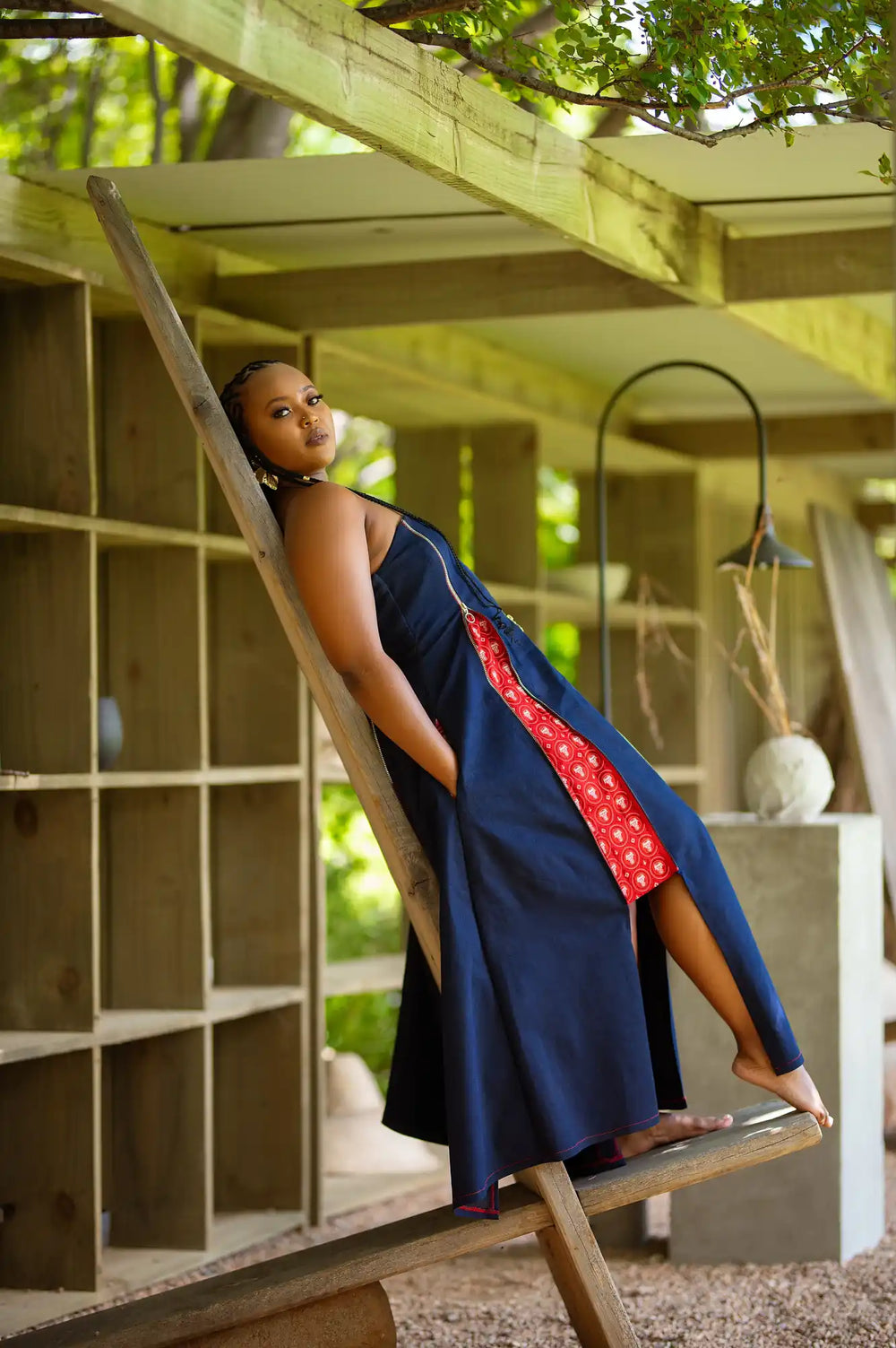 A person in a navy blue dress with red accents relaxes on a swing.