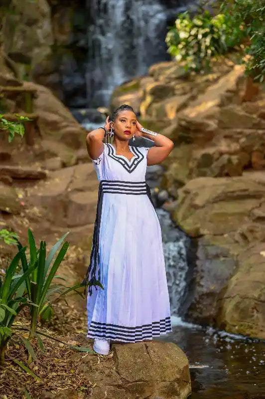 A white sleeveless dress with navy blue striped trim and a v-neckline.